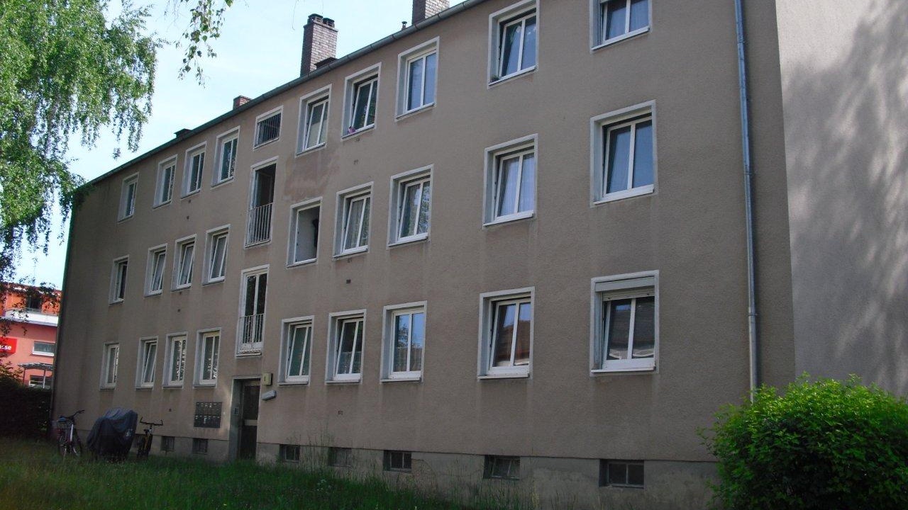 Ein braun-beiges Haus in der Gerhart-Hauptmann-Straße 2-16. Unter einem der Fenster ist die Farbe deutlich dunkler als der Rest der Fassade. Das Gebäude wirkt insgesamt veraltet.