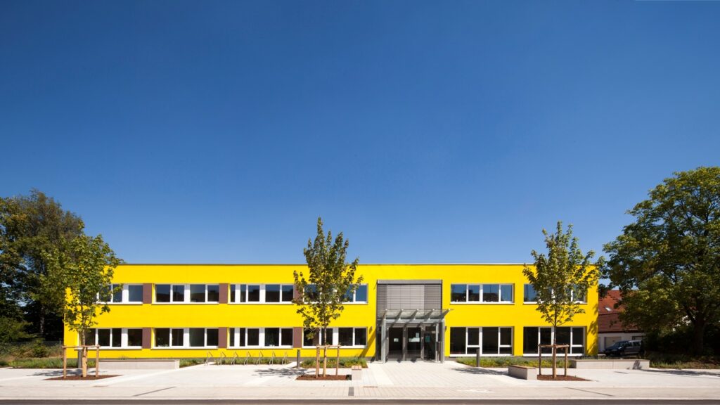 Der Firmensitz der HDWW: Ein modernes Gebäude mit auffallend gelber Fassade und weißen Fenstern.