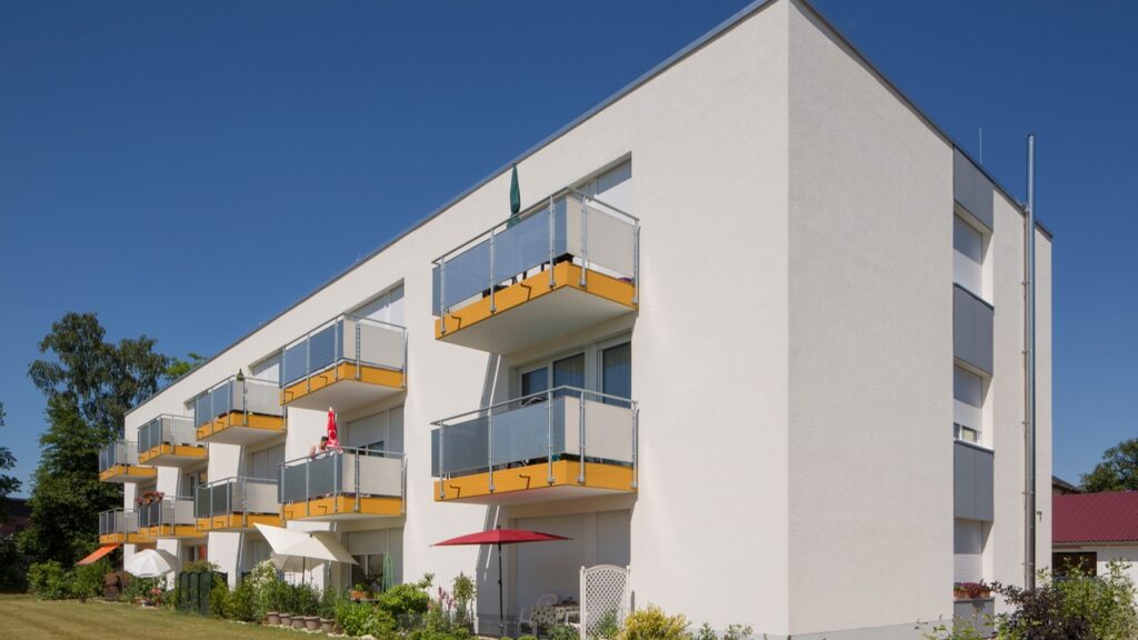 Nach der Renovierung: Gebäude in der Herderstraße 3. Ein stilvolles, modernes Gebäude mit einem sehr hellen Beigeton. Die Balkone sind mit einem gelben Akzent versehen.